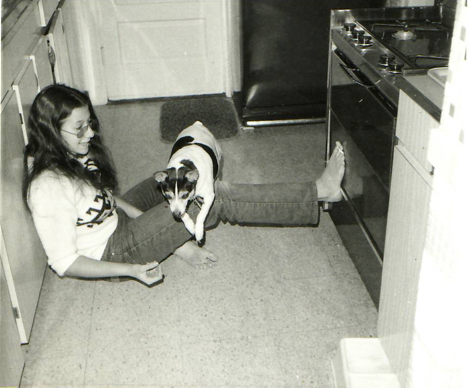 girl sitting on floor with dog jumping over her leg