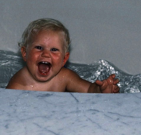 blond haired baby smiling in bathtub