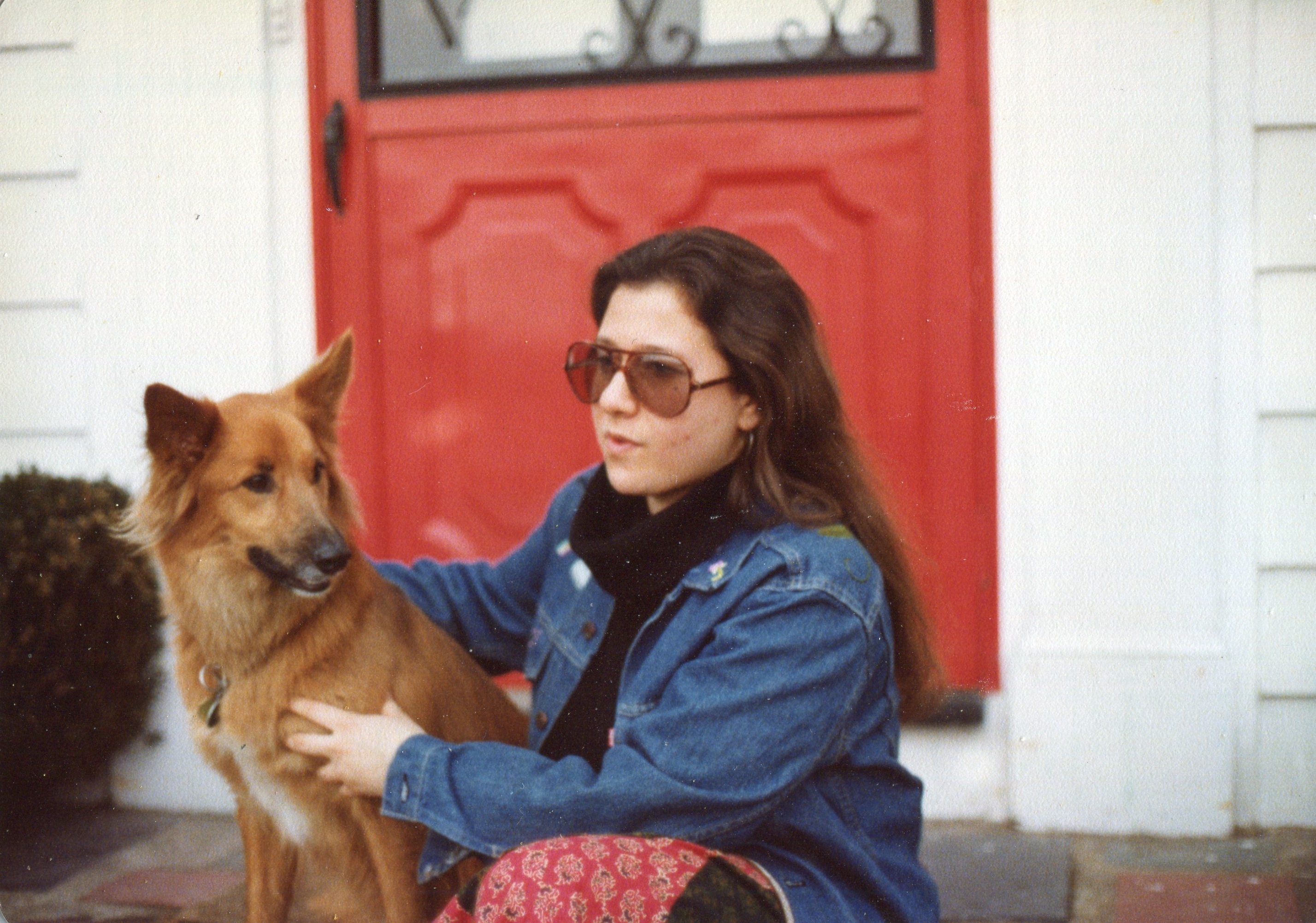 young woman wearing sunglasses sitting on a stoop with a dog