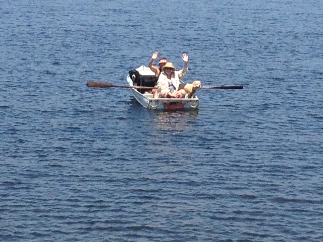 rowboat in lake with 2 people and 2 dogs in it